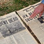 Imagen de archivo de un hombre que muestra un periódico de 1963 que informa sobre el asesinato de Kennedy en el monumento en memoria de John F. Kennedy en Dealey Plaza, el lugar donde fue asesinado, en Dallas, Texas, EEUU. EFE/Larry W. Smith