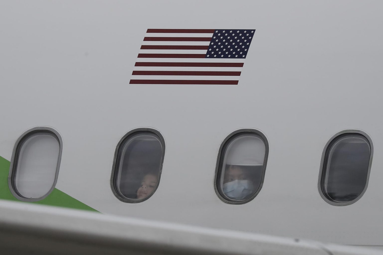 Migrantes provenientes de Estados Unidos observan por la ventana de un avión en el que fueron enviados de regreso a casa. EFE/ Jeffrey Arguedas