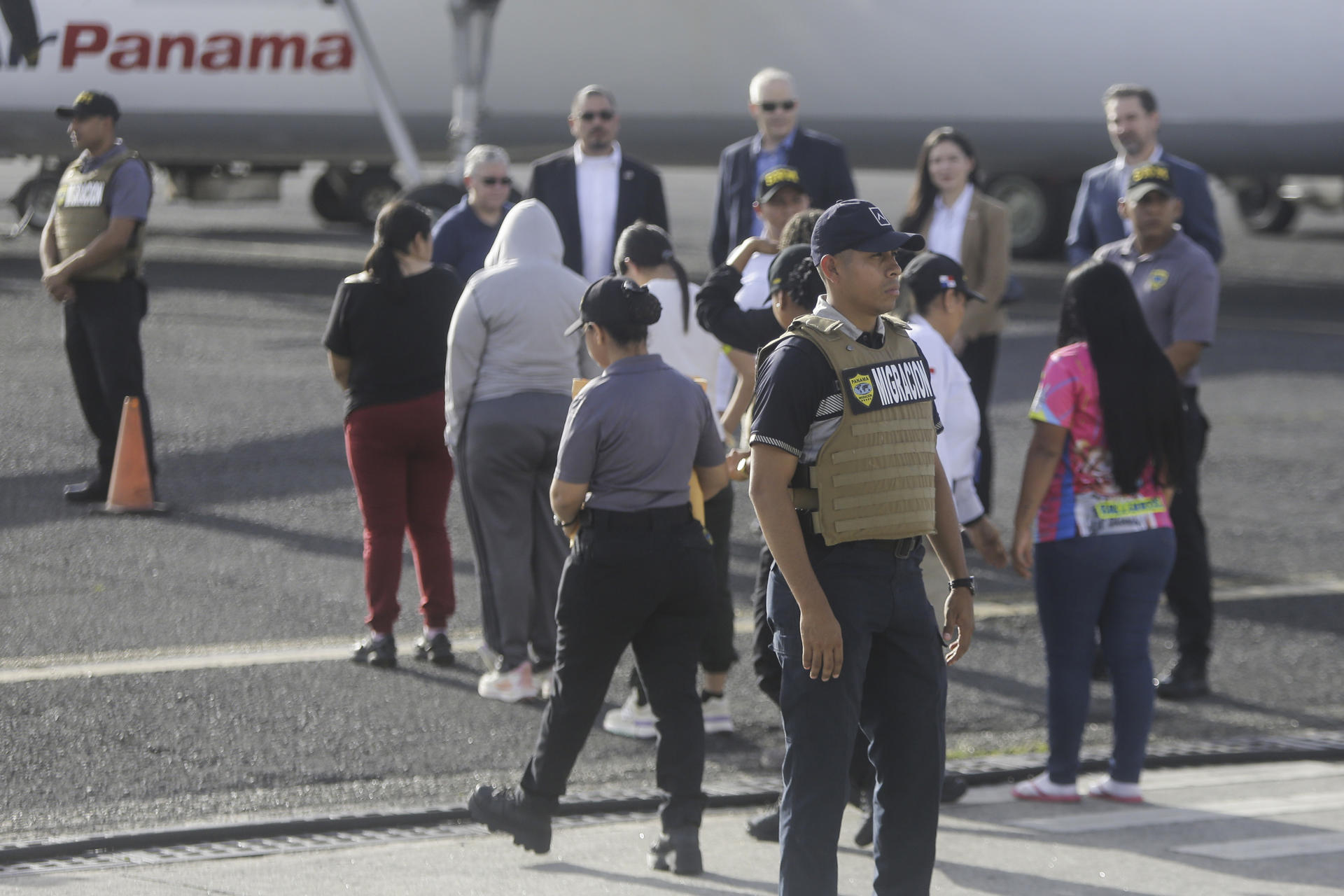 Funcionarios del Servicio Nacional de Migración de Panamá acompañan a migrantes para un vuelo de deportación de Panamá a Colombia este lunes, en el Aeropuerto Internacional Marcos A. Gelabert en la Ciudad de Panamá (Panamá). EFE/ Carlos Lemos
