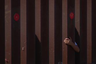 Fotografía de archivo de un niño tocando el muro fronterizo sur entre Estados Unidos y México en San Diego, California (Estados Unidos). EFE/EPA/ALLISON DINNER