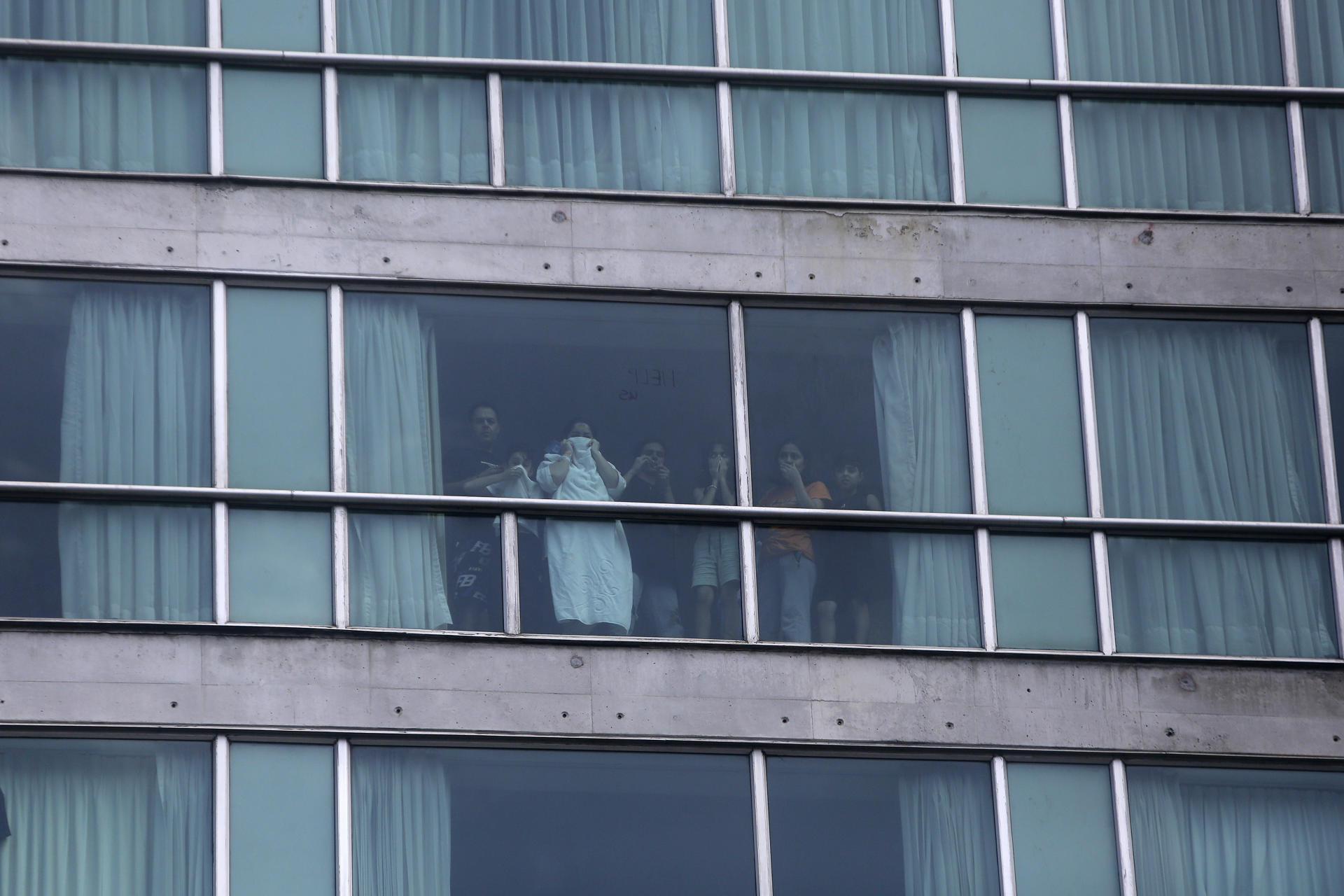 Personas miran desde una ventana del hotel Decápolis este martes, en Ciudad de Panamá (Panamá). EFE/ Carlos Lemos
