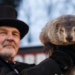 Fotografía de archivo del 2 de febrero de 2017 de un miembro del Club de la Marmota sostieniendo a la marmota Phil, el animal meteorólogo más famoso del mundo, durante la celebración del Día de la Marmota en la pequeña colina de Gobbler's Knob en Punxsutawney, Pensilvania (Estados Unidos). EFE/ David Maxwell