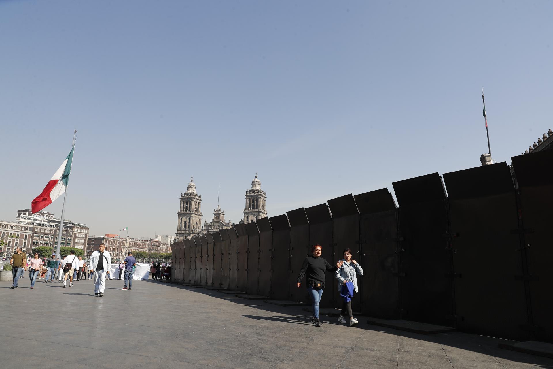 Personas caminan junto a vallas que están protegiendo las inmediaciones de Palacio Nacional este miércoles, en la Ciudad de México (México). EFE/ Mario Guzmán
