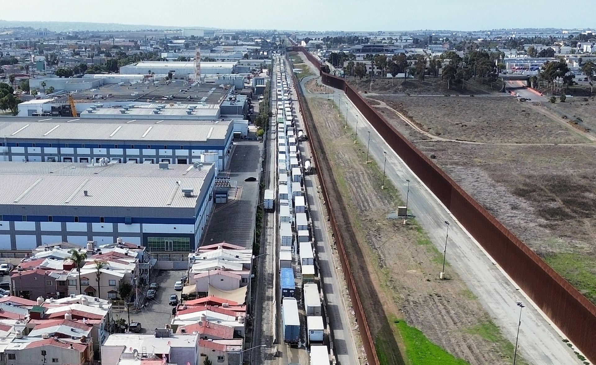 Fotografía aérea donde se observa una fila de vehículos de carga para cruzar una garita hacia EEUU, este miércoles en la ciudad de Tijuana (México). EFE/ Joebeth Terriquez
