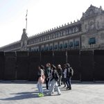 Personas caminan junto a vallas que están protegiendo las inmediaciones de Palacio Nacional este miércoles, en la Ciudad de México (México). EFE/ Mario Guzmán