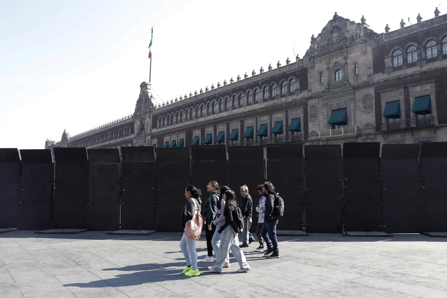 Personas caminan junto a vallas que están protegiendo las inmediaciones de Palacio Nacional este miércoles, en la Ciudad de México (México). EFE/ Mario Guzmán