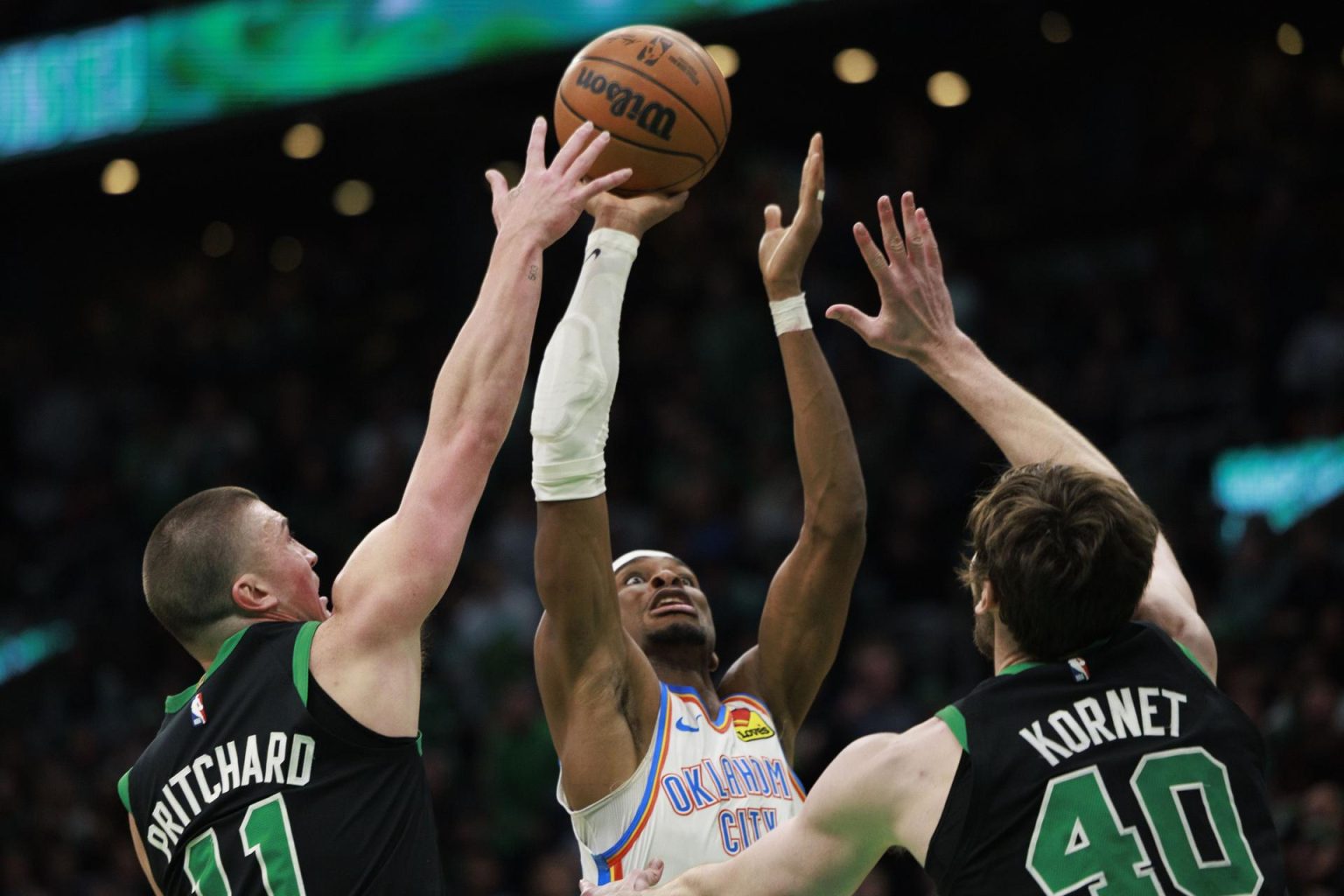 El escolta de Oklahoma City Thunder, Shai Gilgeous-Alexander (c), lanza a canasta ante la presión del escolta de Payton Pritchard (i), y el pívot Luke Kornet (d), durante el partido que ganaron a domicilio este miércoles a Boston Celtics. EFE/EPA/CJ GUNTHER