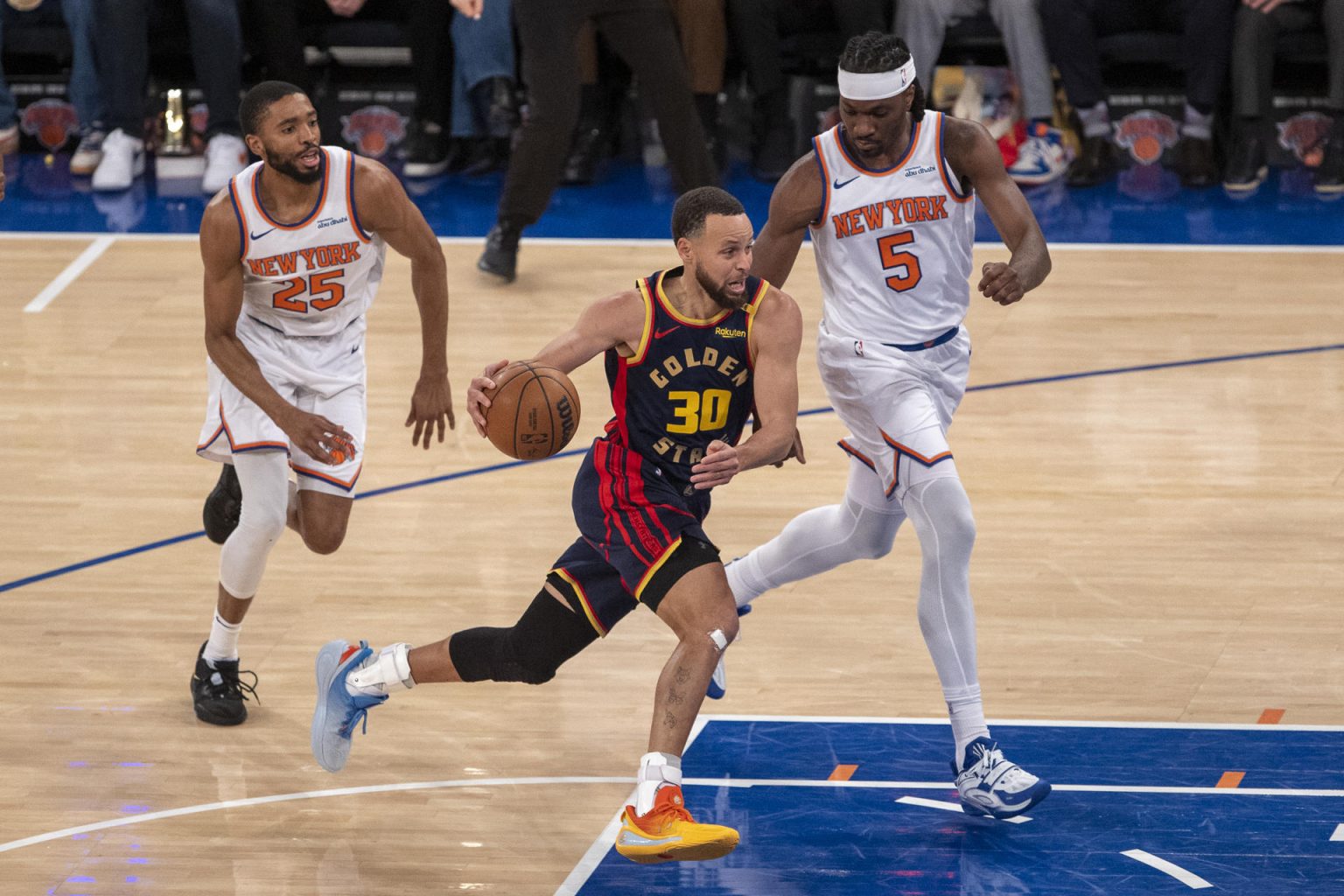 Stephen Curry (c), de los Golden State Warriors, disputa el balón con Mikal Bridges (i), y Precious Achiuwa (d), durante el triunfo ante los New York Knicks en el Madison Square Garden. EFE/ Ángel Colmenares