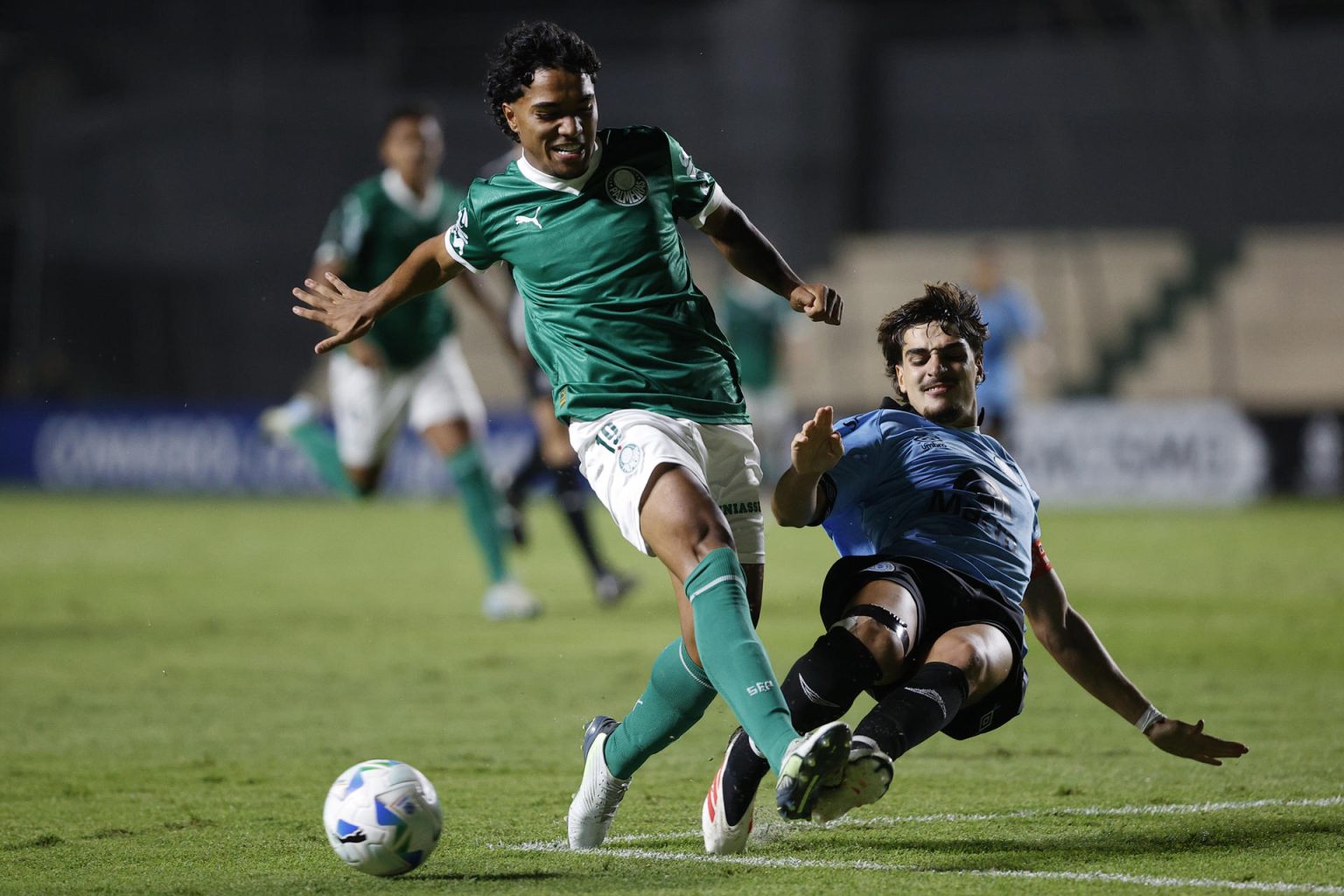 El defensor del Belgrano argentino Francisco Razzeto (d) se arroja al piso para neutralizar el avance del extremo de Palmeiras Heitor durante el partido en el estadio asunceno Arsenio Erico que clasificó este jueves al equipo brasileño a la final de la Copa Libertadores Sub-20, el próximo domingo contra Flamengo. EFE/ Juan Pablo Pino