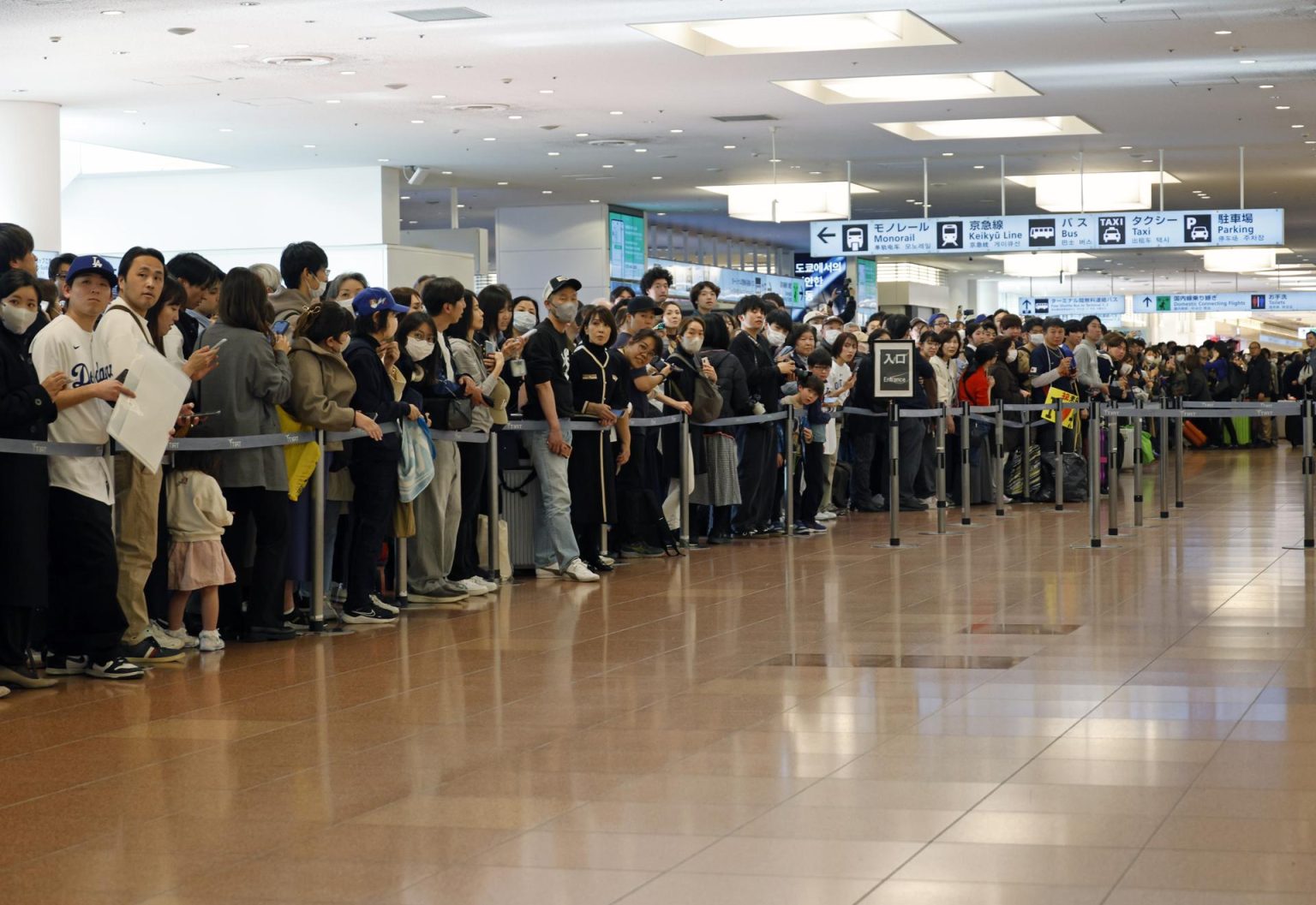 Aficionados al béisbol esperan en el aeropuerto de Haneda, en Tokio, la llegada de Los Angeles Dodgers. EFE/EPA/FRANCK ROBICHON