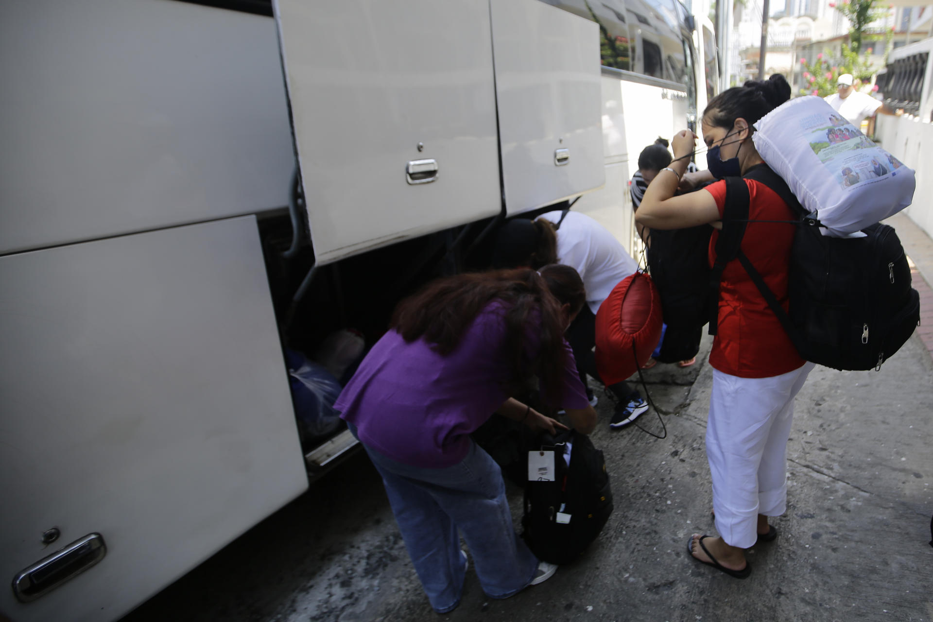 Migrantes se preparan para subir a un bus este martes, en Ciudad de Panamá (Panamá). Migrantes que fueron expulsados de Estados Unidos salen de un hotel de la capital panameña rumbo a las instalaciones de Fe y Alegría, la organización religiosa que les proporcionara ayuda. EFE/ Carlos Lemos
